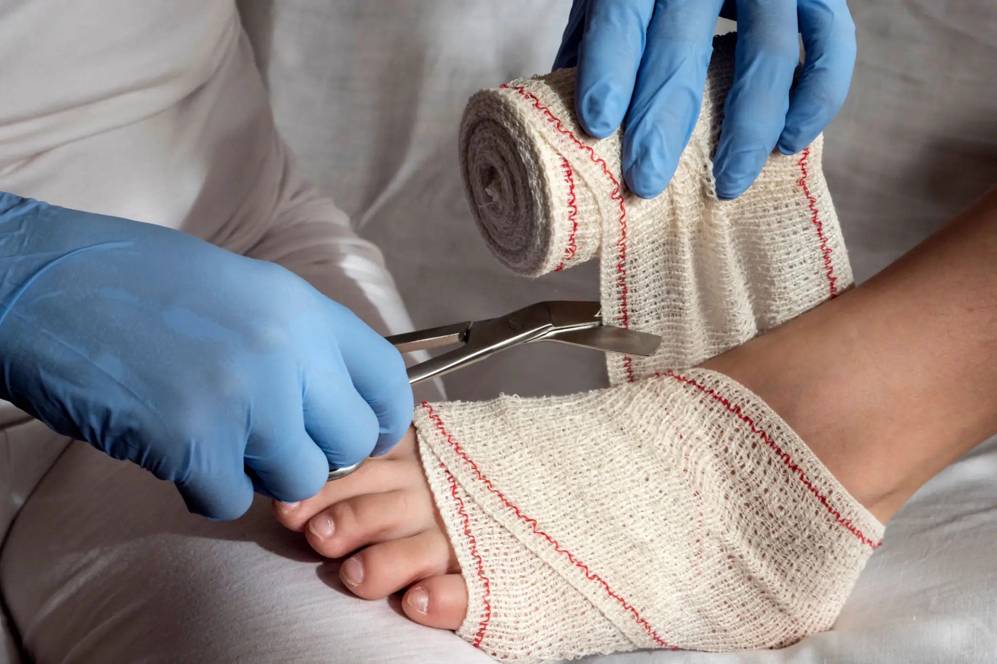Medical professional cutting a bandage on a patient's foot.